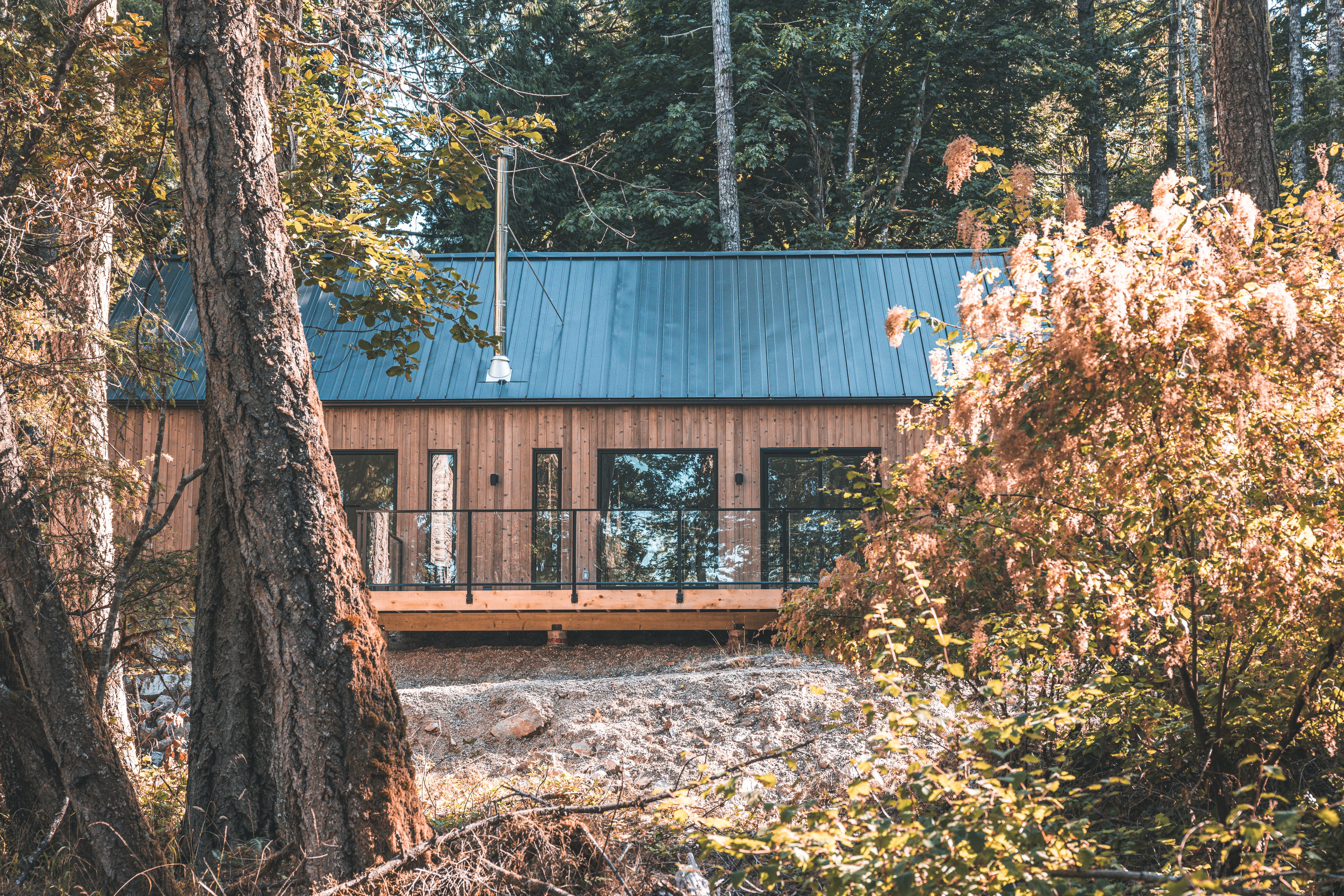 Cedar-clad Blend home and deck in a forested setting.