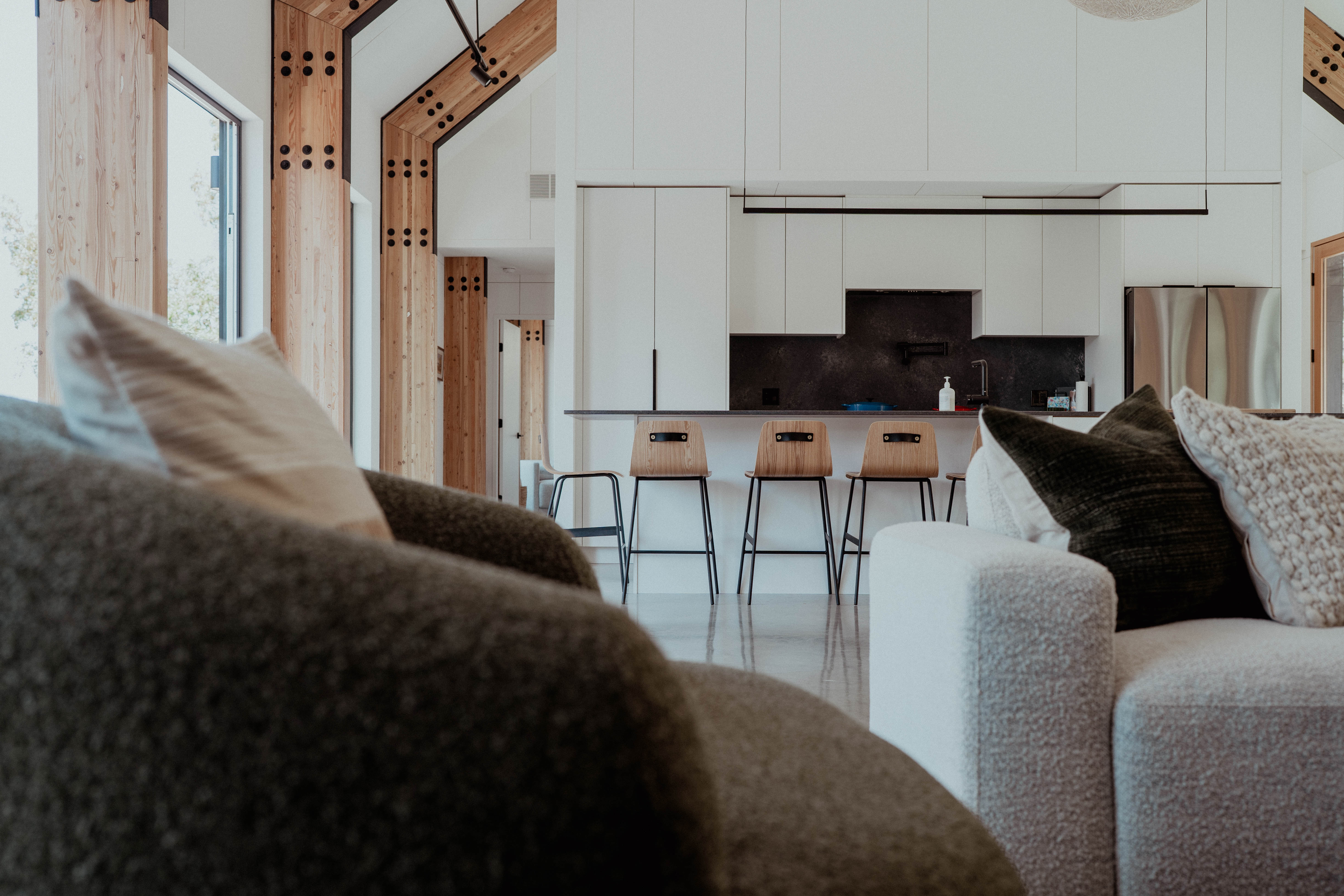 Living area facing a white kitchen framed by exposed timber.
